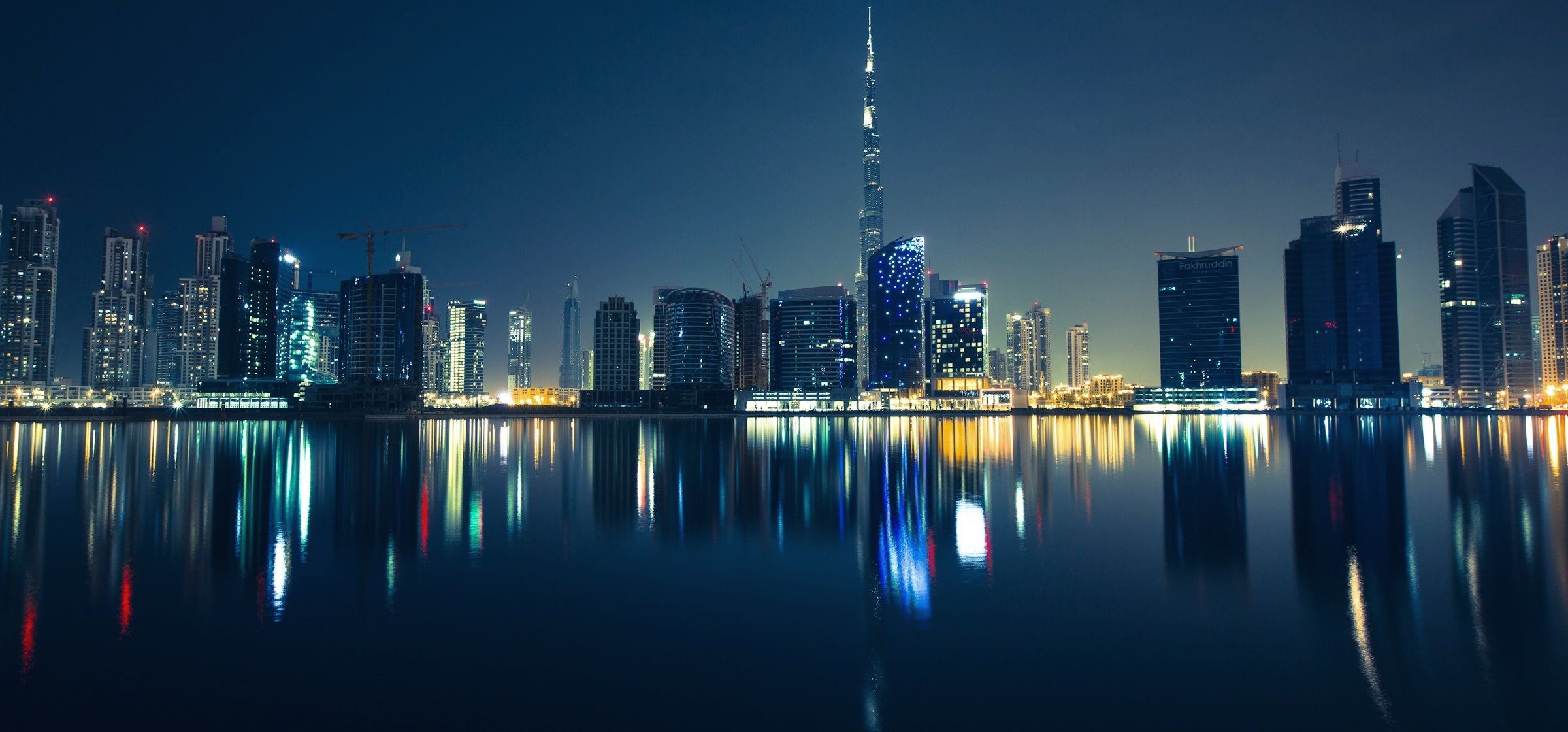 Dubai skyline at night, with Burj Khalifa reflected in the water